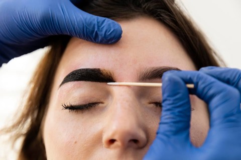 Woman getting eyebrow treatment from beautician