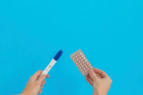 Hand holding contraceptive pills pregnancy test