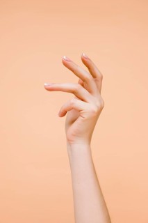 Sideview woman s hand pale orange background