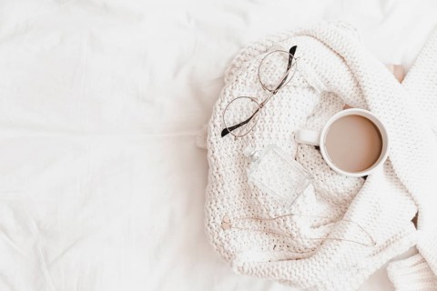 Hot drink necklace eyeglasses perfume sweater placed bedsheet