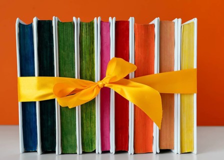 Rainbow books stack with yellow ribbon