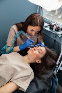 Beautician doing eyebrow treatment her female client
