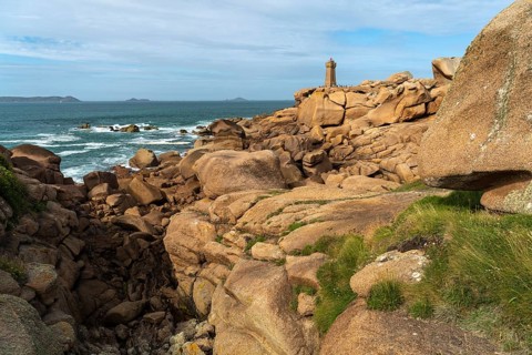 The rocks of the pink granite coast Cote de Granit Rose and the lighthouse Phare de Ploumanac'h near Ploumanac'h