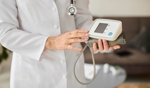 Elder covid recovery center female doctor holding blood pressure monitor