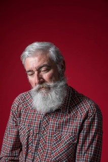 Portrait depressed senior man against red background