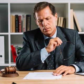 Serious mature lawyer reading document desk courtroom