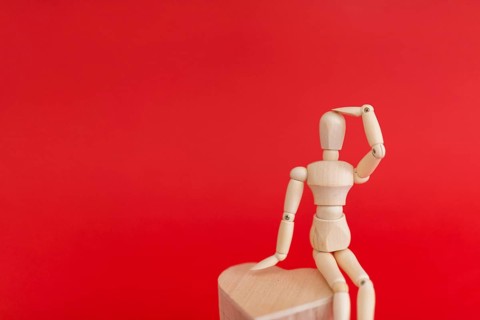 Wooden mannequin sitting wooden heart