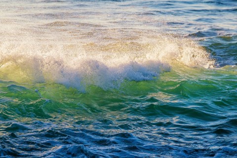 Breaking ocean wave on sunset backlit with sun. Fonte da Telha