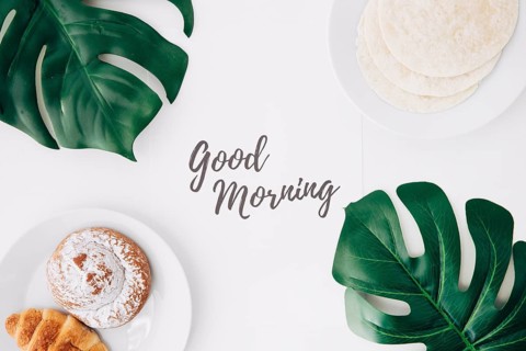 Fresh flour tortillas baked bun croissant breakfast with good morning text paper green monster leaves white background