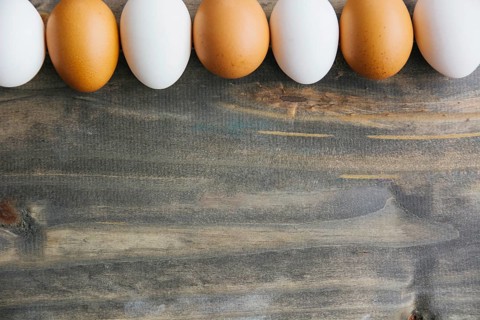 Row brown white eggs wooden background