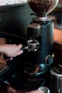 Crop hands grinding coffee into portafilter