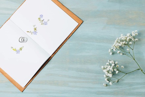 Love text made with wedding rings open book with gypsophila flower wooden backdrop