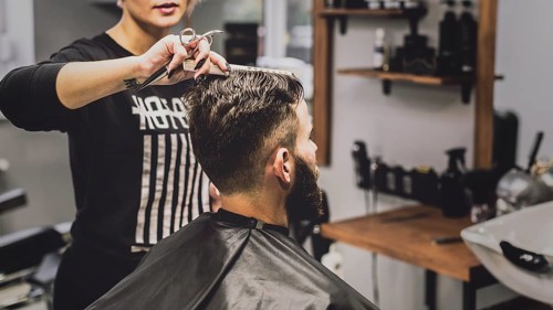 Woman combing haircutting man