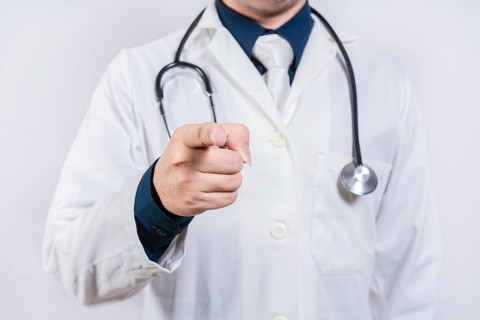 Unrecognizable doctor pointing at the camera. Doctor hands pointing at you isolated