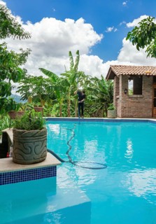 Person cleaning swimming pool with vacuum suction hose. Man cleaning a swimming pool with suction hose