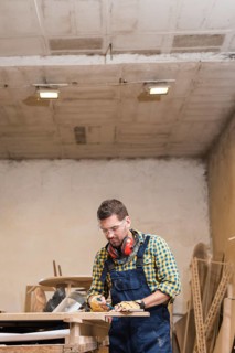Professional male carpenter taking measurement workbench workshop