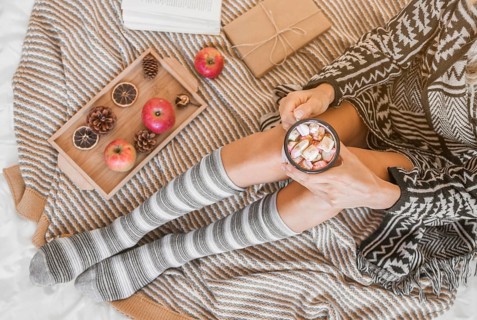 Woman with hot chocolate relaxing bed