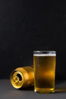 Front view beer can beside glass with beer