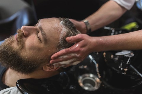 Crop hairdresser washing hair client