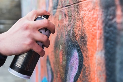 Man s hand drawing graffiti wall with aerosol can