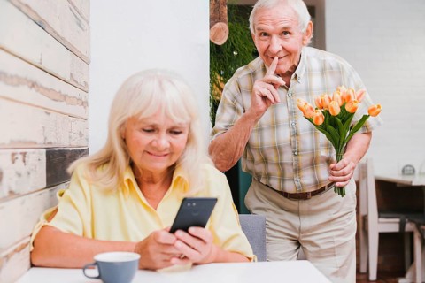 Elderly man preparing surprise with bouquet wife