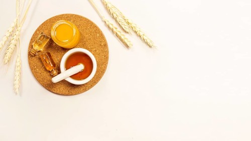 Essential oil honey brown cork with wheat ears against white backdrop
