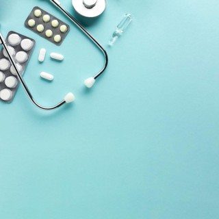 Stethoscope with blister packed medicines against blue background