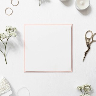 Blank white paper surrounded with rings gypsophila string candles scissor white background