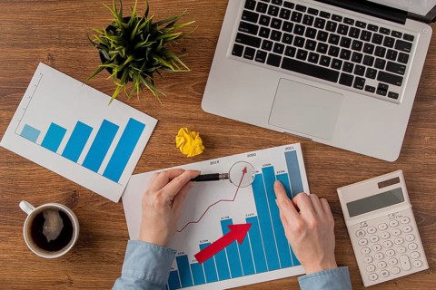 Top view office desk with laptop growth chart analyzed by hands