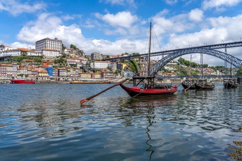 View over the traditional Rabelo boats on the Douro riverbank in Vila Nova de Gaia towards the old town of Porto and the bridge Ponte Dom Luis I