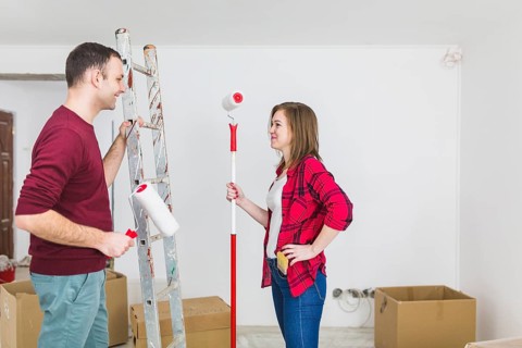 Side view couple with paint rollers ladder