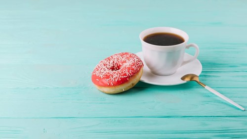 Yummy donut with cup tea spoon green table