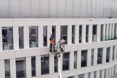 Two workers wearing safety harness wash walls