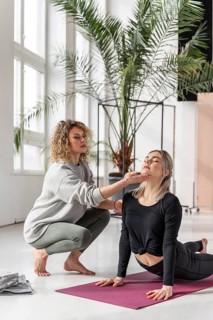Teacher helping woman with pose