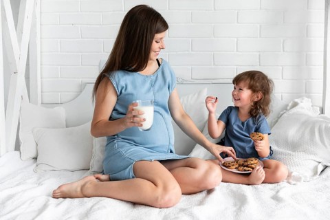 Long shot mother daughter eating chocolate cookies