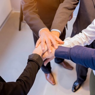 Close up businesspeople stacking hands meeting office