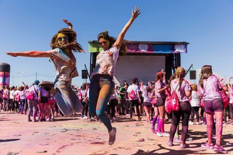 Excited young women jumping air celebrating holi festival