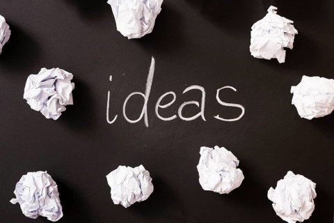 Ideas word surrounded with white crumpled paper balls blackboard