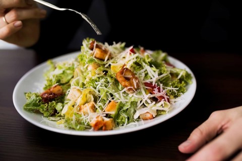 Person eating tasty caesar salad with croutons restaurant