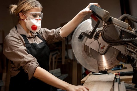 Side view female carpenter using round saw