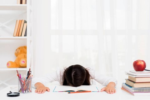 Tired schoolgirl lying copybook