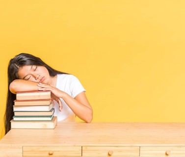 Pile books desk woman sleeping