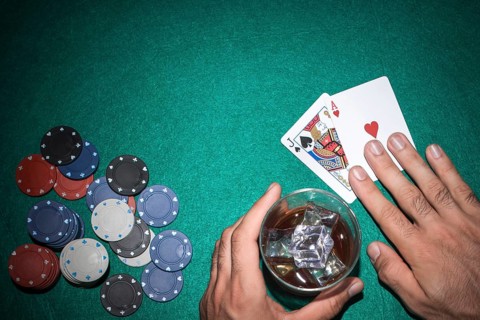 Poker player showing jack ace card with casino chips green poker table