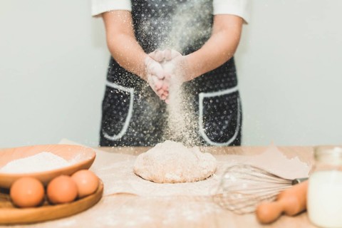 Woman making bread pouring flour