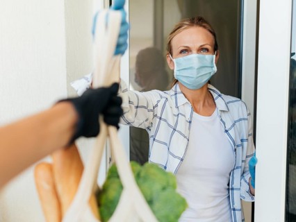 Woman with medical mask home picking up her groceries self isolation