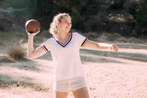 Cheerful teen schoolgirl playing rugby