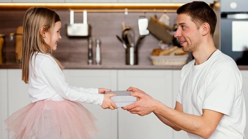 Side view smiley girl tutu skirt giving her dad present father s day
