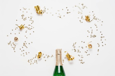 Top view champagne bottle with golden ribbons confetti