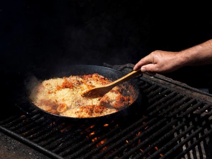 Cook mixing rice with calamari rings vegetables frying pan