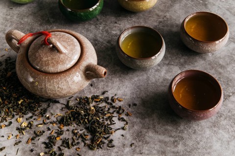 Chinese brown teapot teacups with tea herbs concrete backdrop